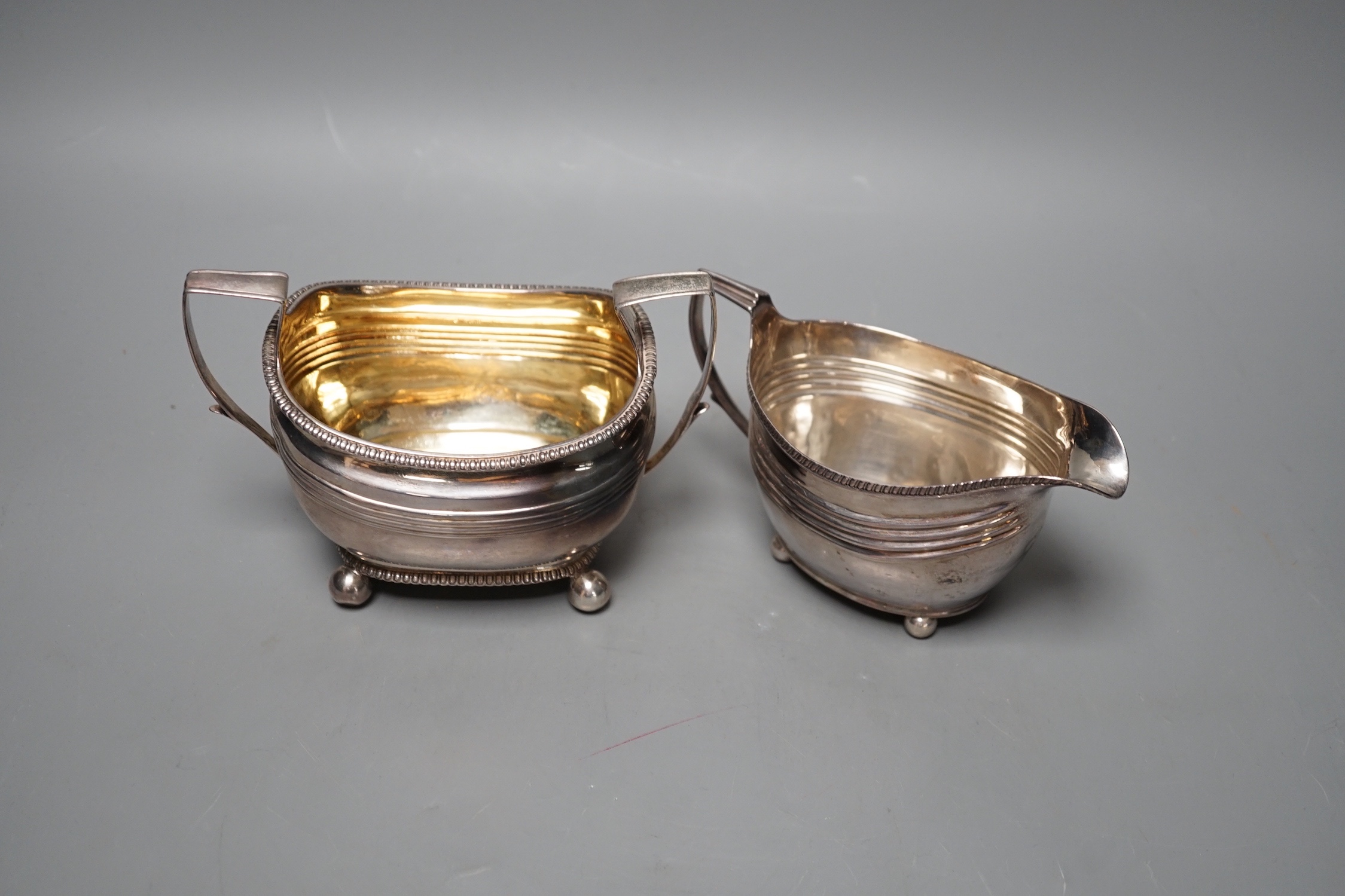A George III silver cream jug, London, 1809 and a Georgian silver sugar bowl (marks rubbed), 11oz.